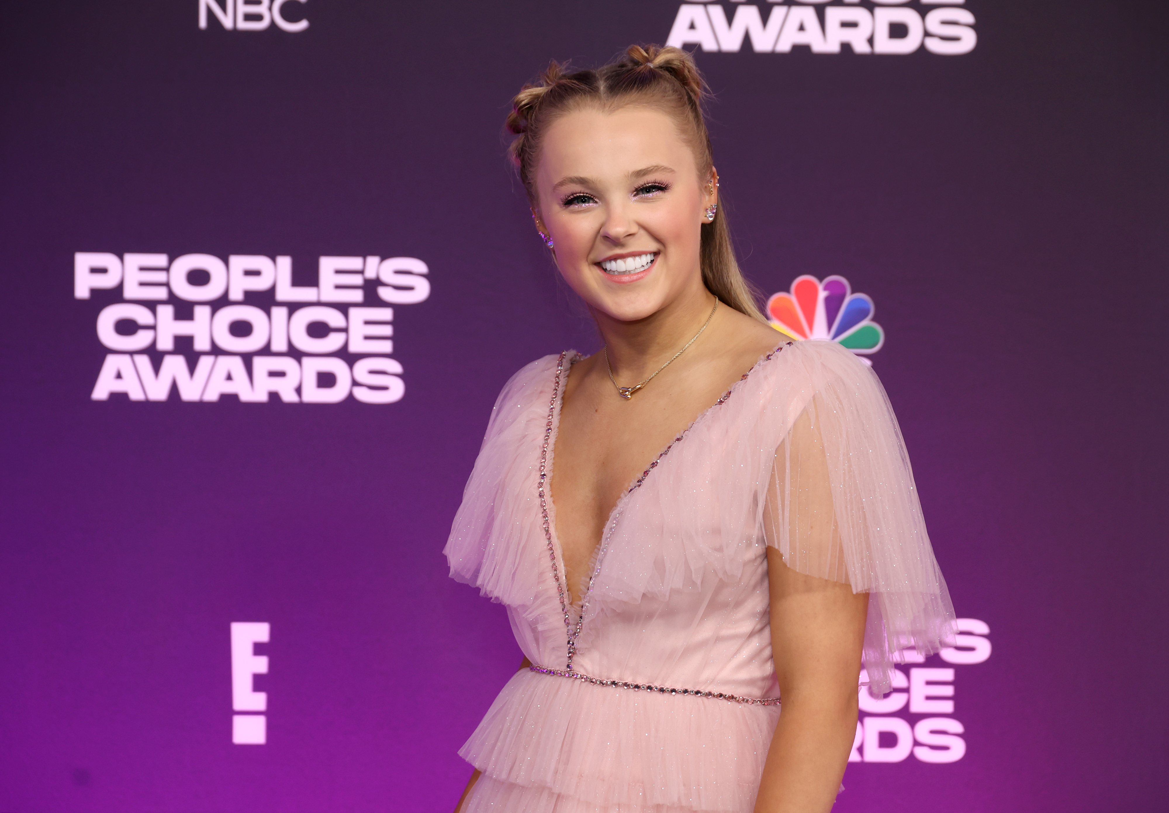 JoJo smiling on the red carpet wearing a tulle dress with a deep V neckline at an awards event