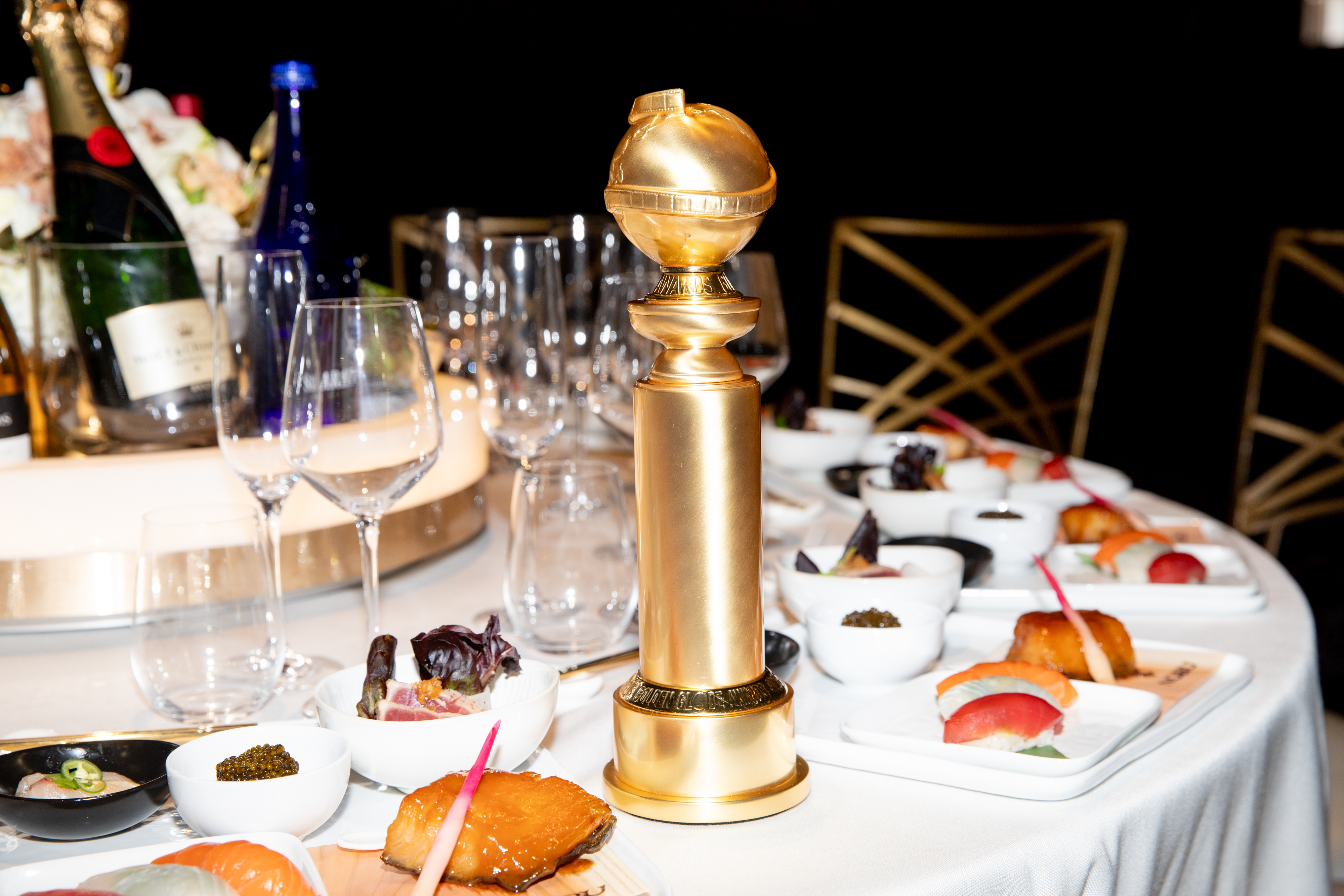 Golden Globe award on a dining table with sushi and drinks at an elegant event setting