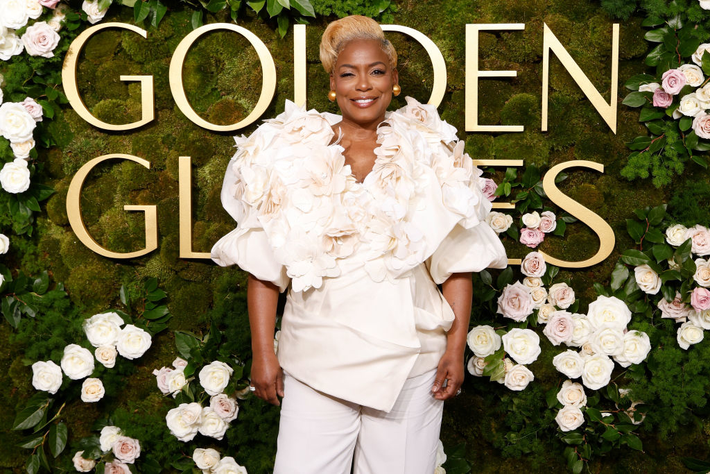 Aunjanue Ellis-Taylor in a floral, puff-sleeve top and pants, posing at Golden Globes event with flower backdrop