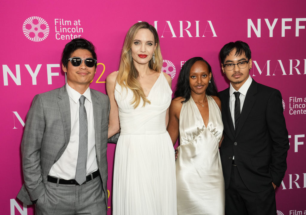 Four people pose for a photo at a film festival event; two wear suits and ties, and two wear elegant white dresses