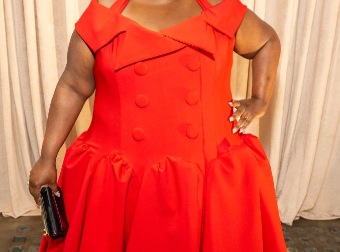 Danielle Pinnock in an elegant dress with a pleated skirt on the red carpet, holding a clutch