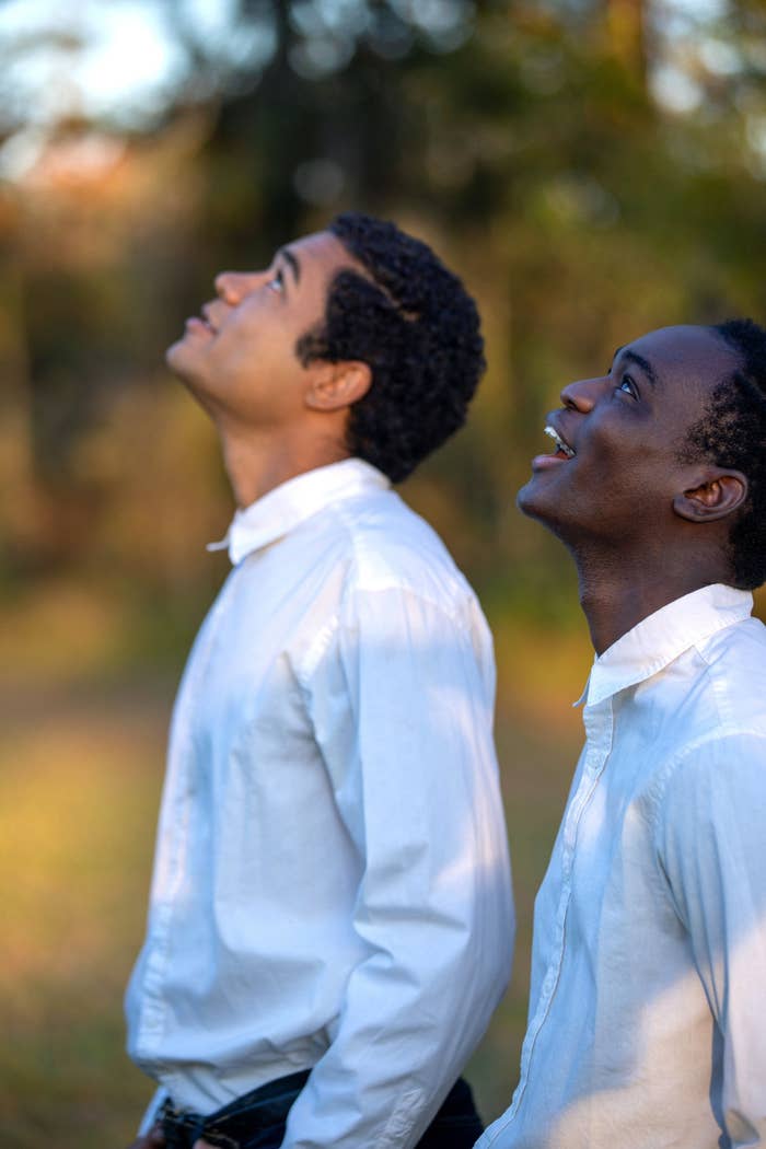 Two people in white shirts looking up outdoors, smiling