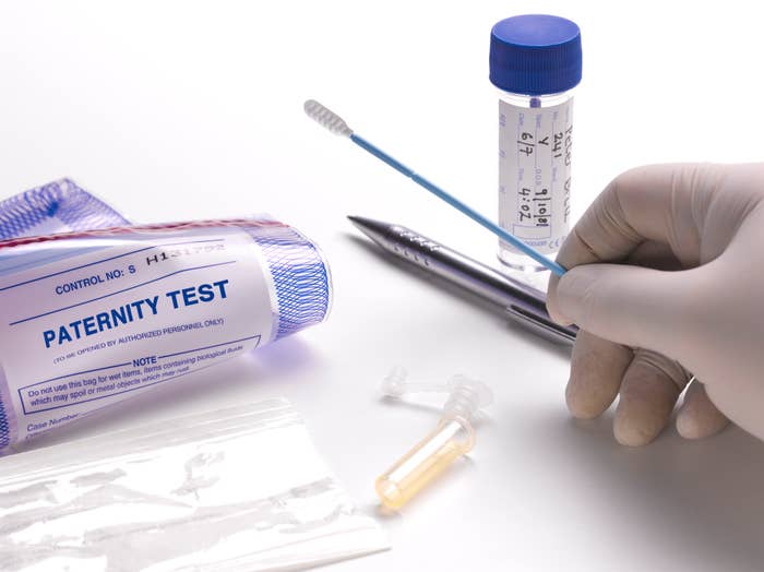 Paternity test kit with a swab, vial, pen, and test instructions; gloved hand holding the swab