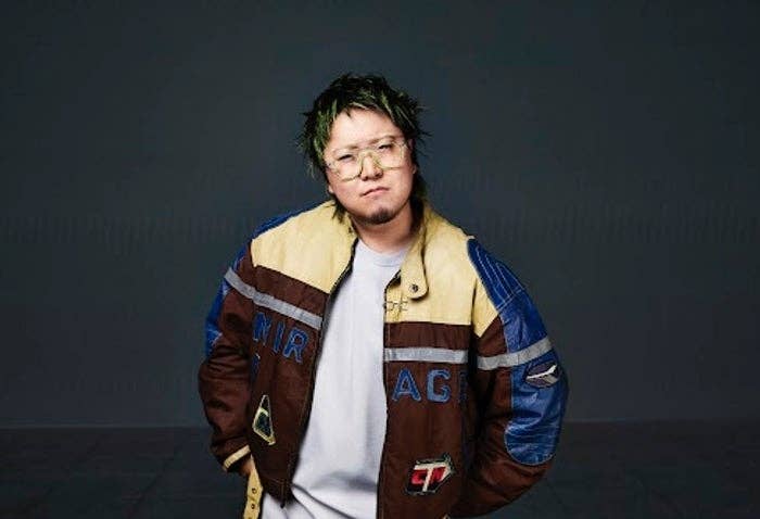 人がスタイリッシュなジャケットを着てポーズをとっています。背景はシンプルです。