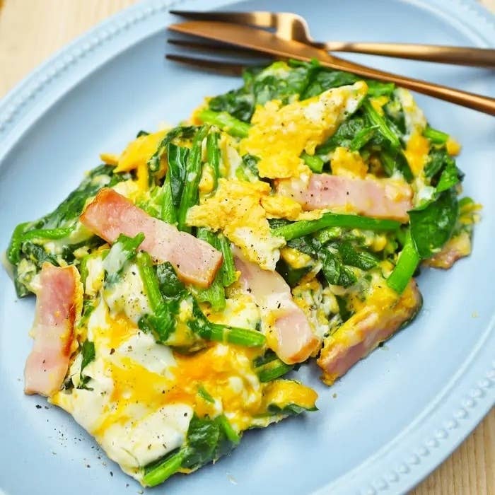 皿に盛られたほうれん草とベーコンの炒め物。フォークとナイフが添えられている。