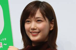 革新的な広告イベントで、女性がシンプルなブラウスを着用し、笑顔でカメラを見ている姿。