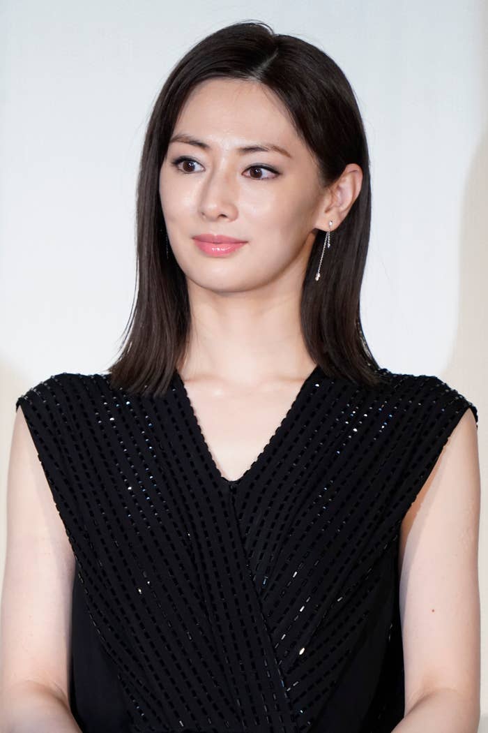 女性が黒いドレスを着て微笑んでいる。