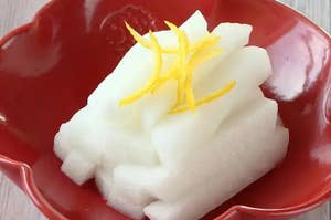 赤い器に盛られた大根の短冊切りに、細切りの柚子が載せられている。