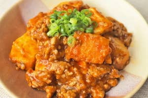 麻婆豆腐の皿に乗った料理。刻んだネギがトッピングされています。