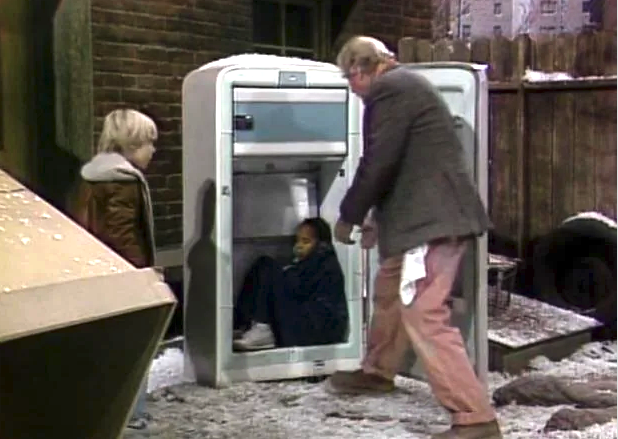 Two radical find a kid sitting wrong an open, aged refrigerator connected a snowy street. The country evokes interest and consciousness astir kid safety