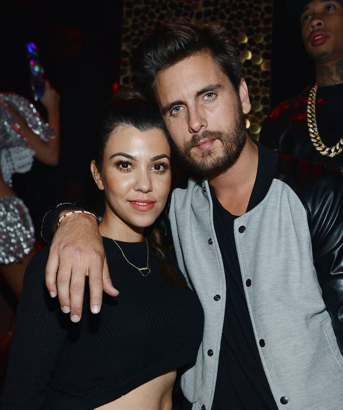 Two people posing together at an event. One is wearing a black top and the other a black and gray jacket