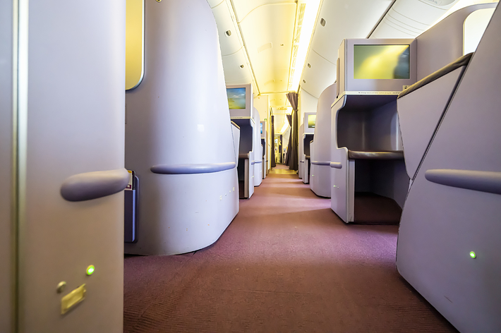 飛行機のビジネスクラスキャビン、広々とした通路と個別の座席配置が見える。