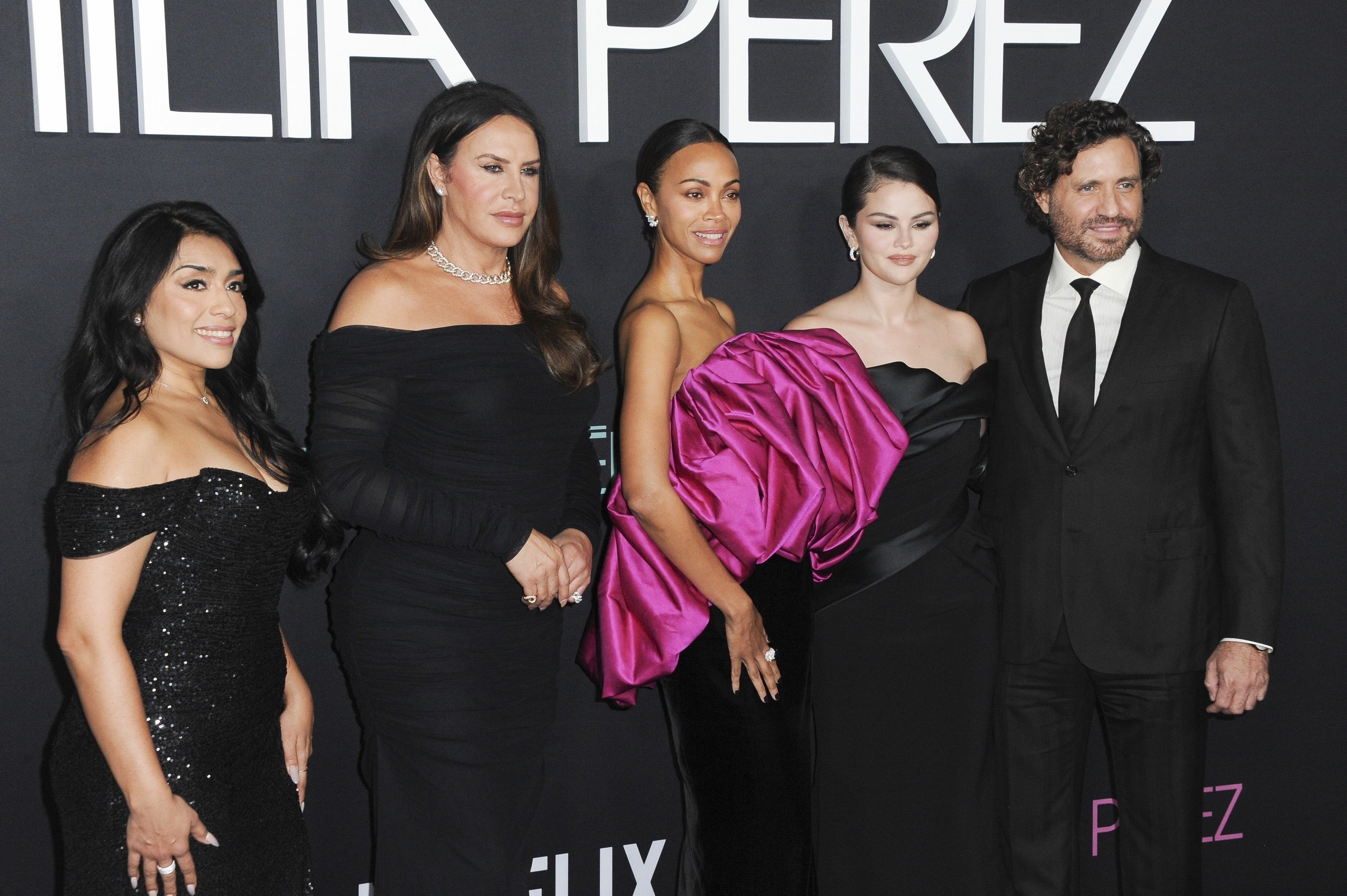 Zoe Saldana of five people on a red carpet, with the women wearing elegant gowns and the man in a suit and tie