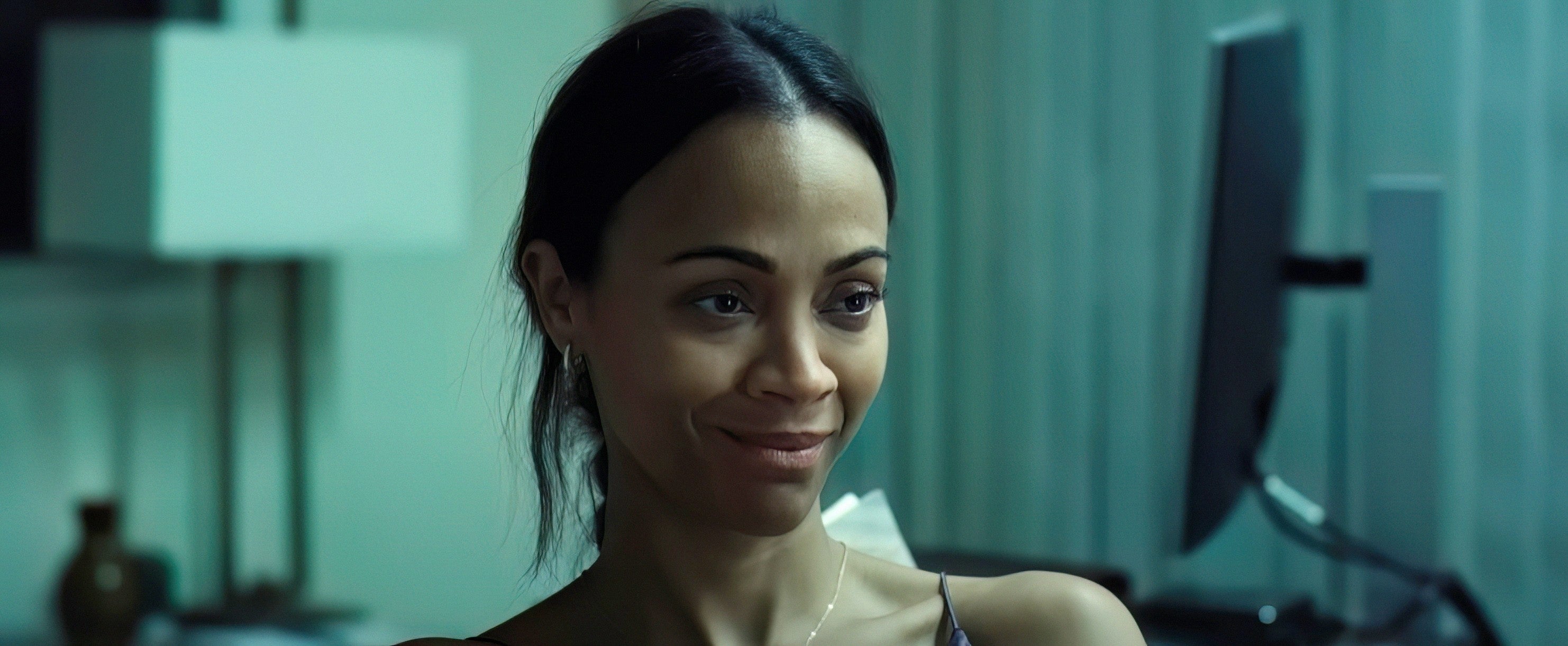 Zoe Saldana in a relaxed setting, seated indoors, with soft lighting and a gentle expression