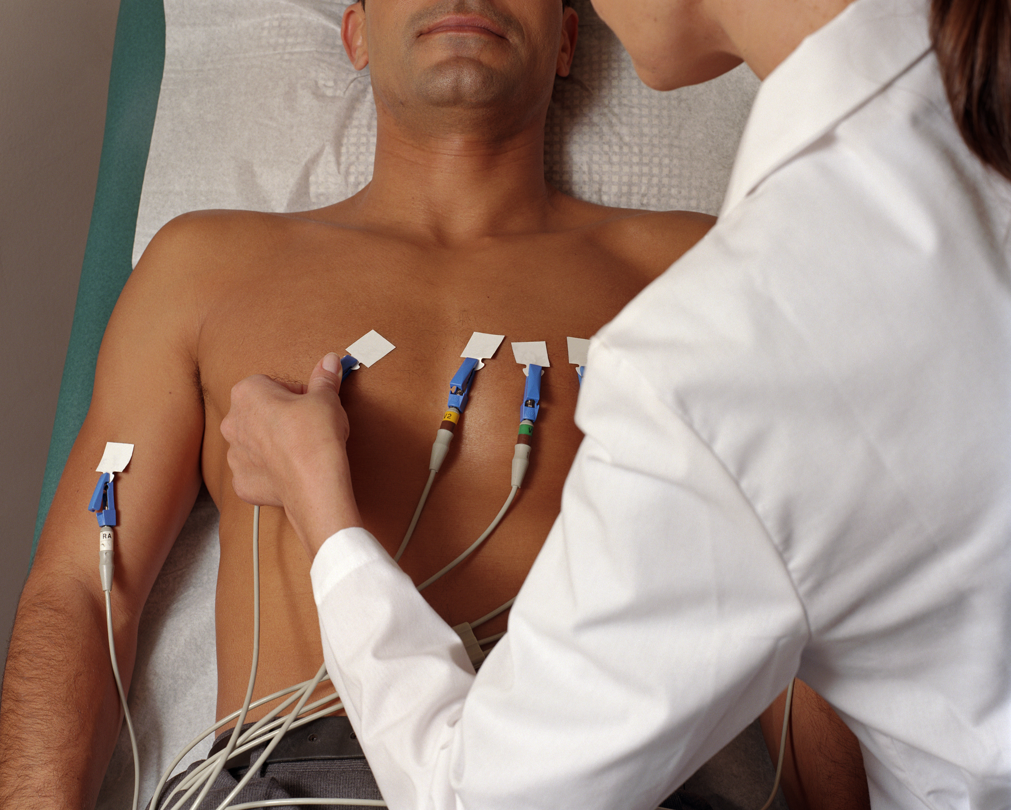 Person som gjennomgår en elektrokardiogram (EKG) -test, med elektroder festet til brystet, overvåket av en helsepersonell