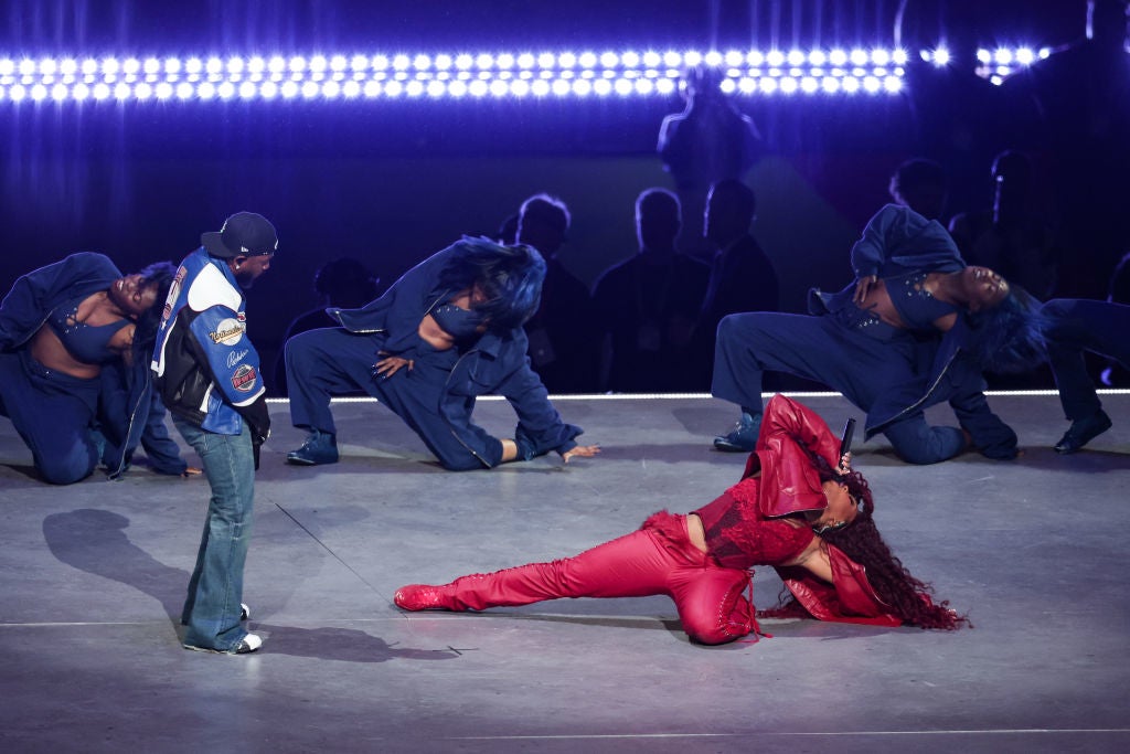 one in a dynamic dance pose in a vibrant outfit, others standing and crouching in coordinated fashion