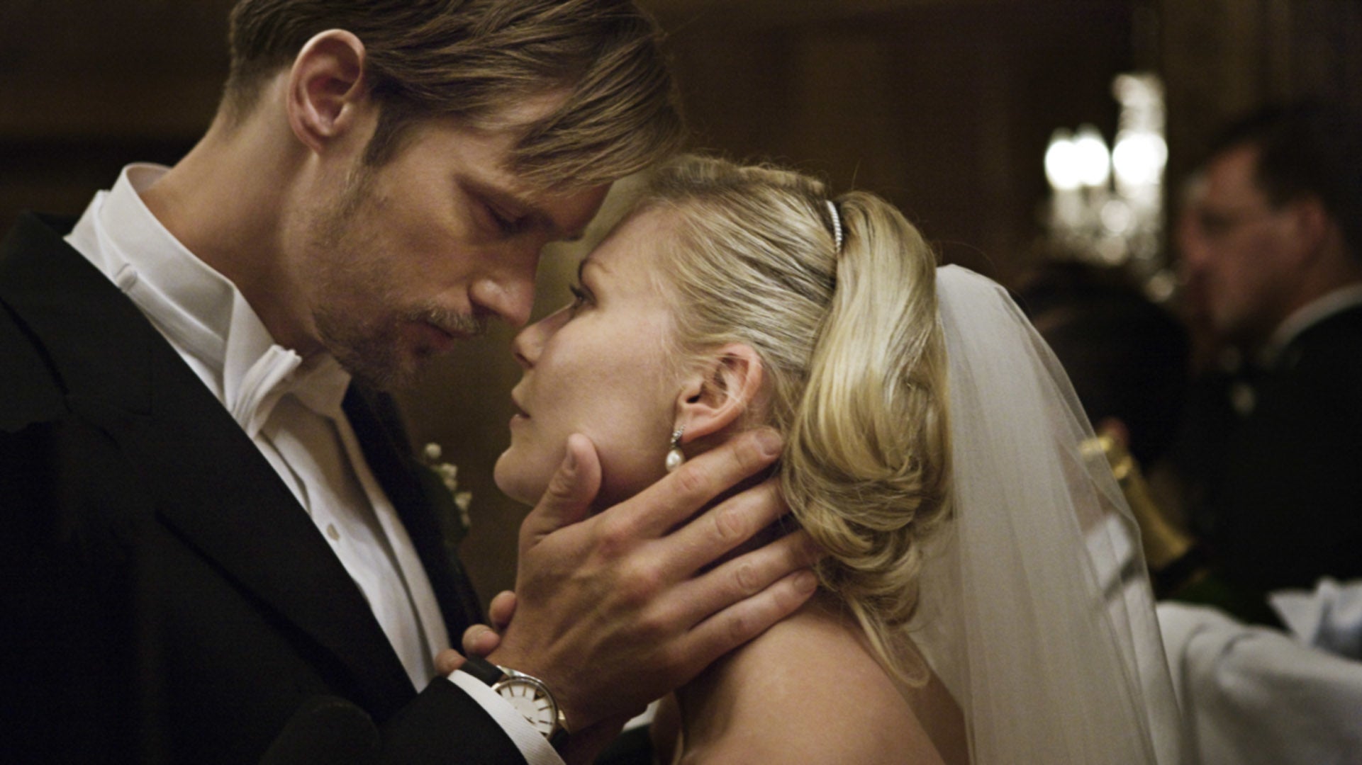 A couple in formal attire shares an intimate gaze at a wedding reception
