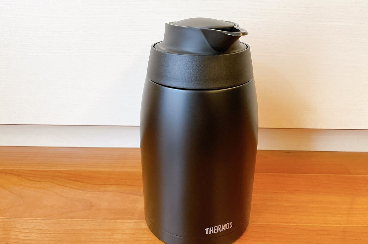 黒いサーマスブランドの断熱ボトルが木製テーブルの上に置かれています。