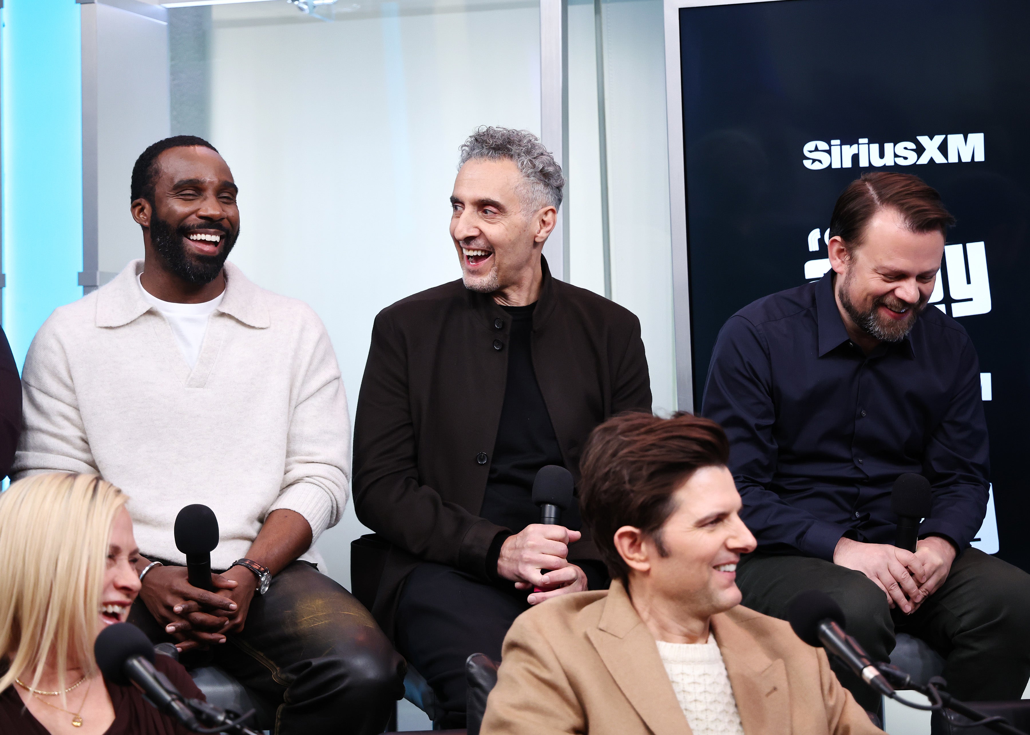 Cast of "Severance" smiling and talking during a SiriusXM interview, holding microphones in a studio setting