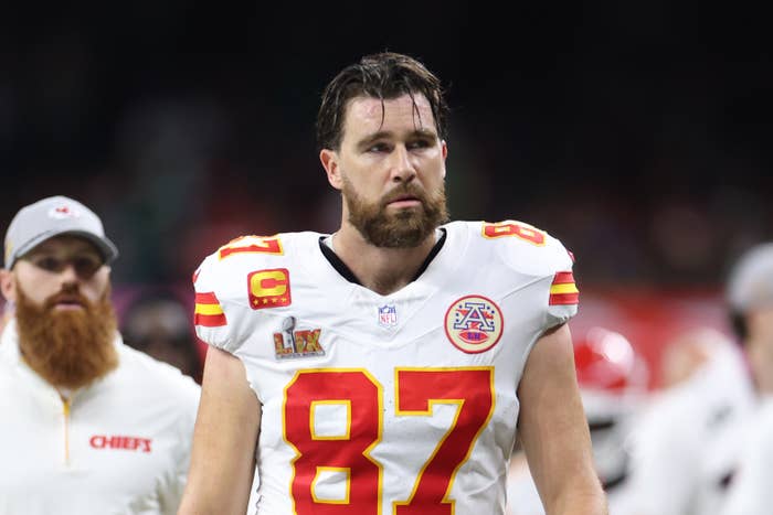 Athlete in football uniform with number 87 walks on the field. Wearing white jersey and red details. Stands out with focused expression