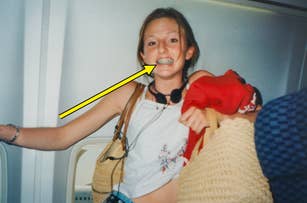 Teen on plane, smiling with braces; wearing a sleeveless top and headphones around neck, holding a woven bag and a red jacket over shoulder