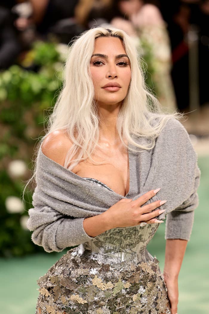 Kim K posing confidently, wearing a shimmering silver corset-style gown