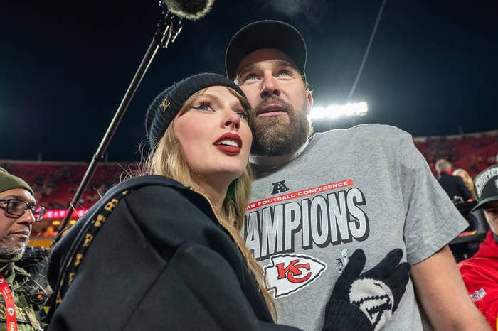 Taylor Swift and Travis Kelce wearing casual attire stand closely on a football field.