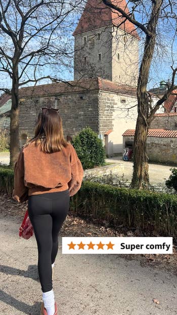 Reviewer in cozy jacket and black leggings walks in a park;