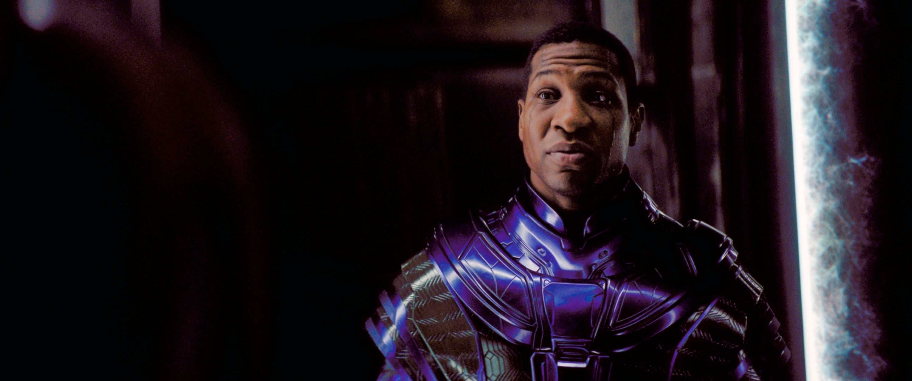 Jonathan Majors wearing a futuristic, armored outfit, standing indoors