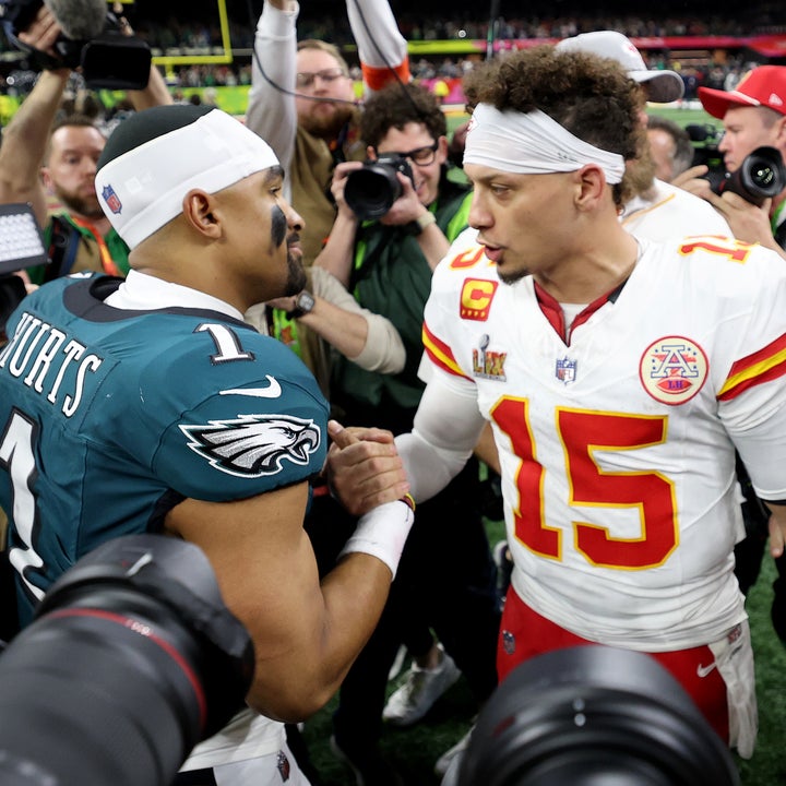 Patrick Mahomes  and Jalen Hurts shake hands on the field after the Super Bowl, surrounded by media and cameras, after a game