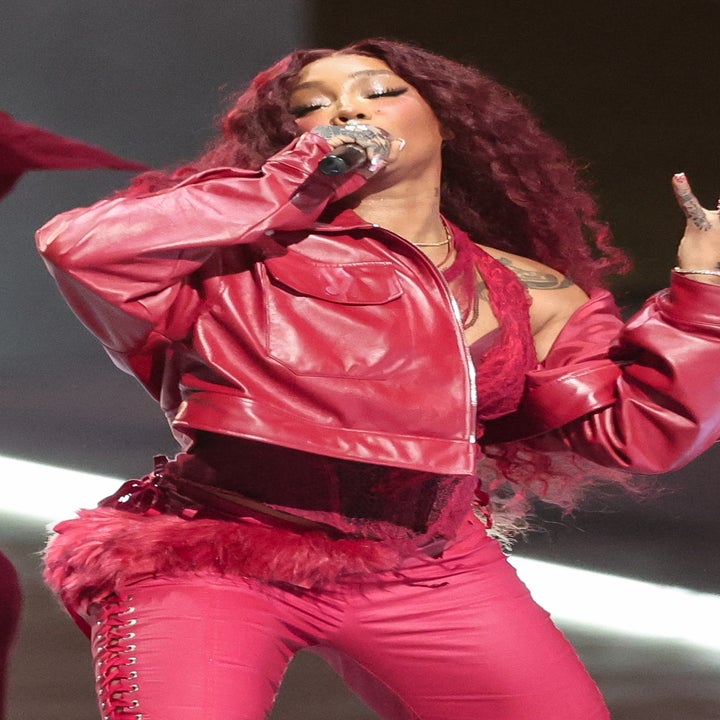 SZA performing energetically on stage in a stylish leather outfit, surrounded by backup dancers