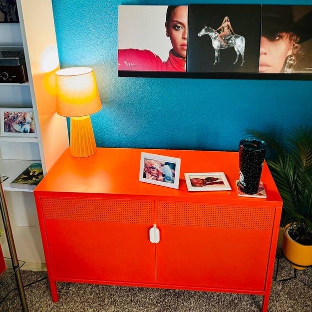 Home decor setup with a sun-themed and celebrity photo wall, vibrant console table, and a separate striped frame mirror for stylish interior shopping