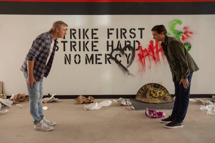 Two people face off in a room with graffiti saying 