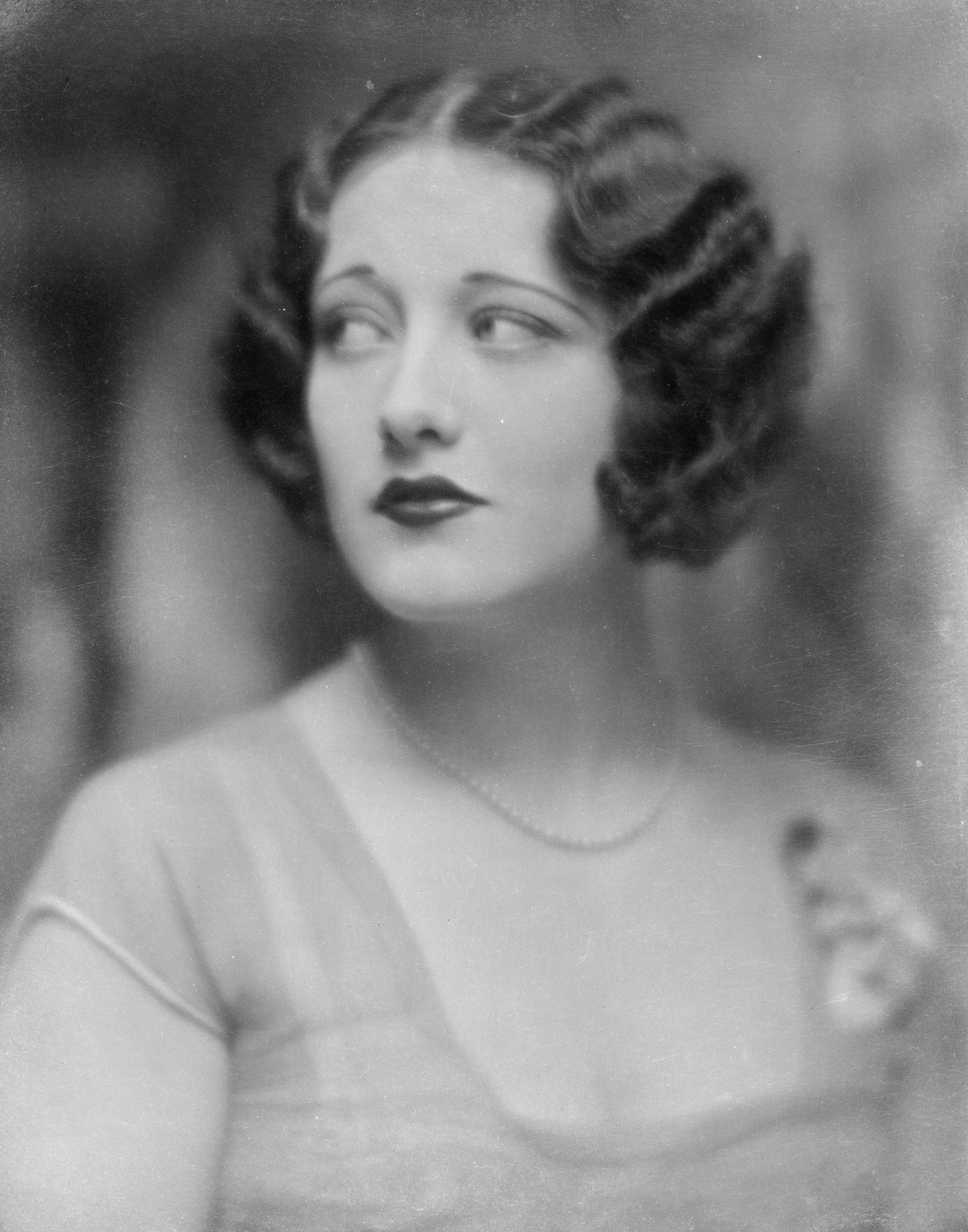 A vintage portrait of a woman with wavy bob hairstyle, wearing a simple dress and subtle jewelry, looking to the side with a contemplative expression