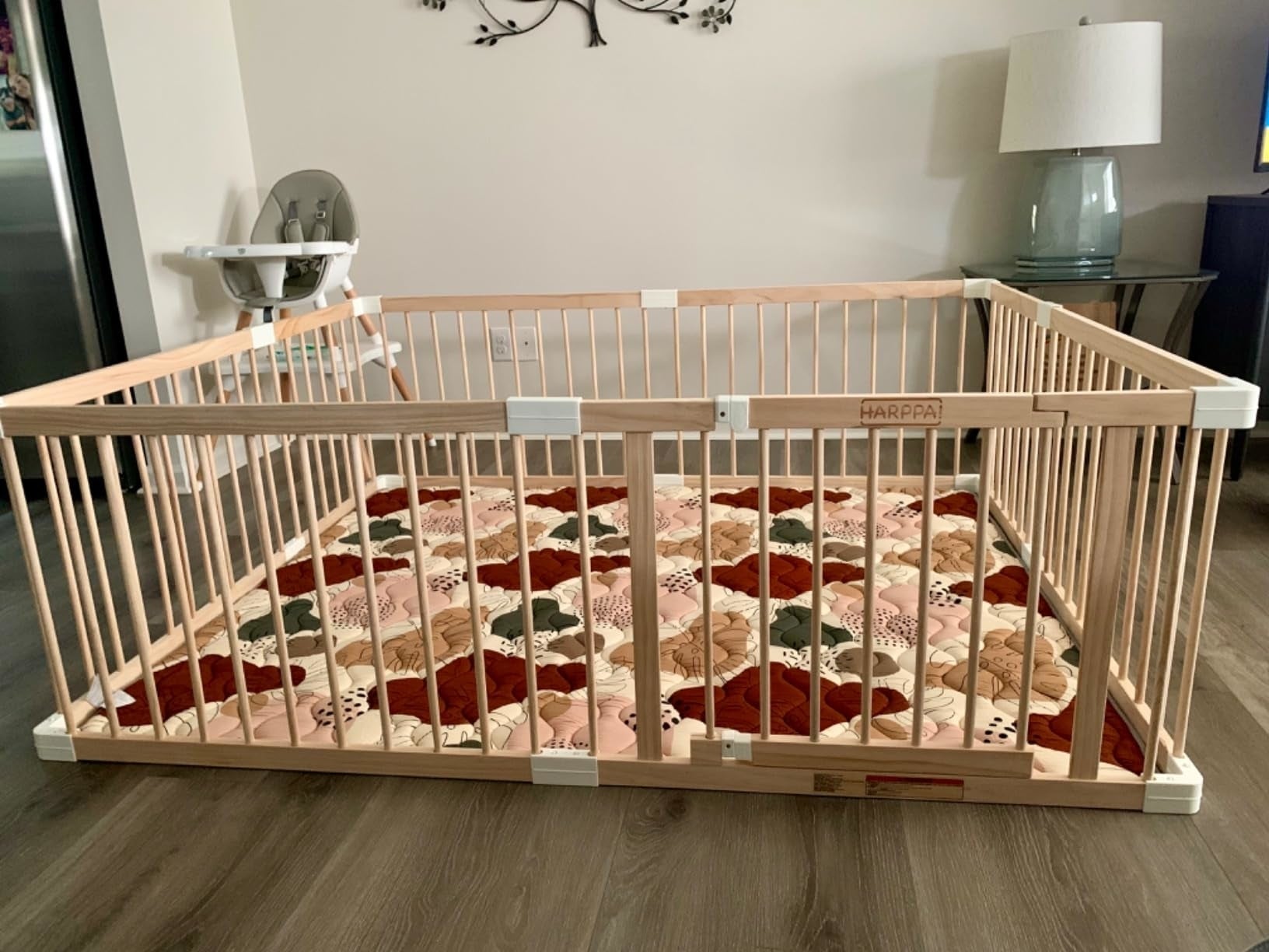 Baby playpen with woody  bars connected  a patchwork mat, adjacent  to a precocious   seat  and lamp successful  a surviving  country   setting