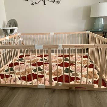Baby playpen with woody bars connected a patchwork mat, adjacent to a precocious seat and lamp successful a surviving country setting
