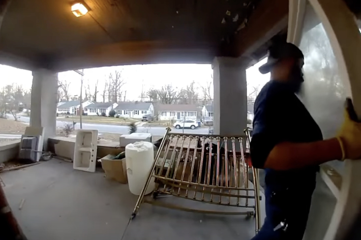 男性がポーチでドアを運んでいる。奥には住宅街の風景が見える。