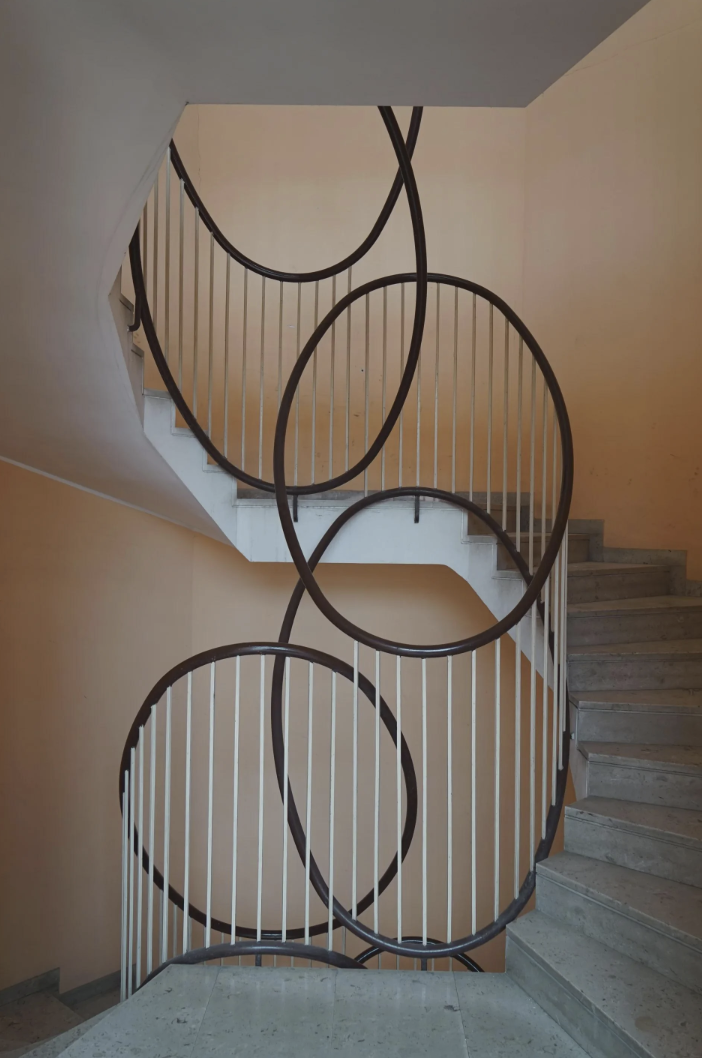 Spiral staircase with unique curved railings and beige walls