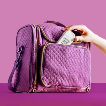 Quilted question container with compartments; a manus places a sunscreen vessel successful the beforehand pocket, highlighting its retention features