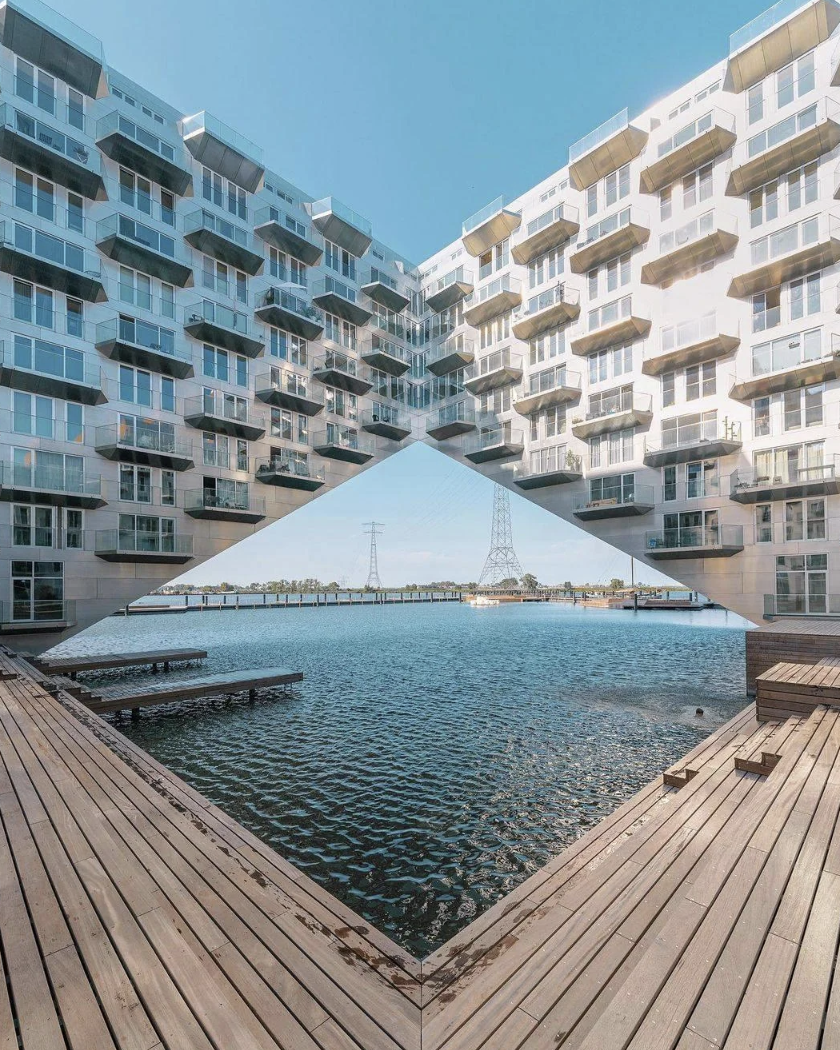 Architectural illusion: A building appears split over water, creating an eye-catching visual, with wooden decks leading to a calm waterway