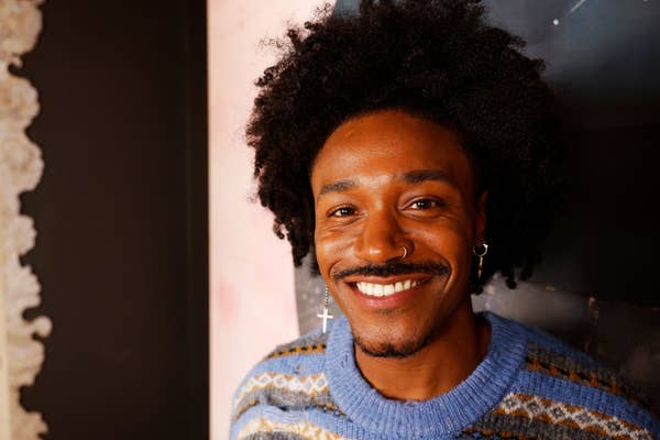 Person smiling, wearing a patterned sweater and hoop earrings
