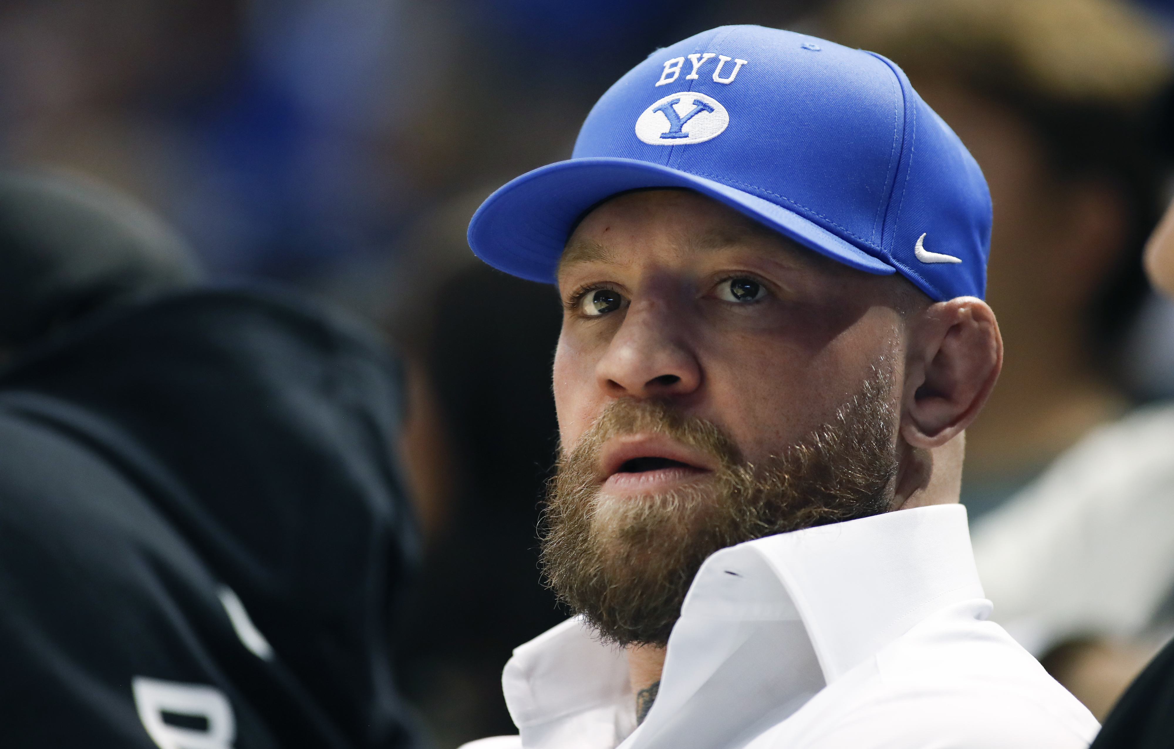 Conor Mcgregor wearing a BYU cap and white shirt, looking ahead.