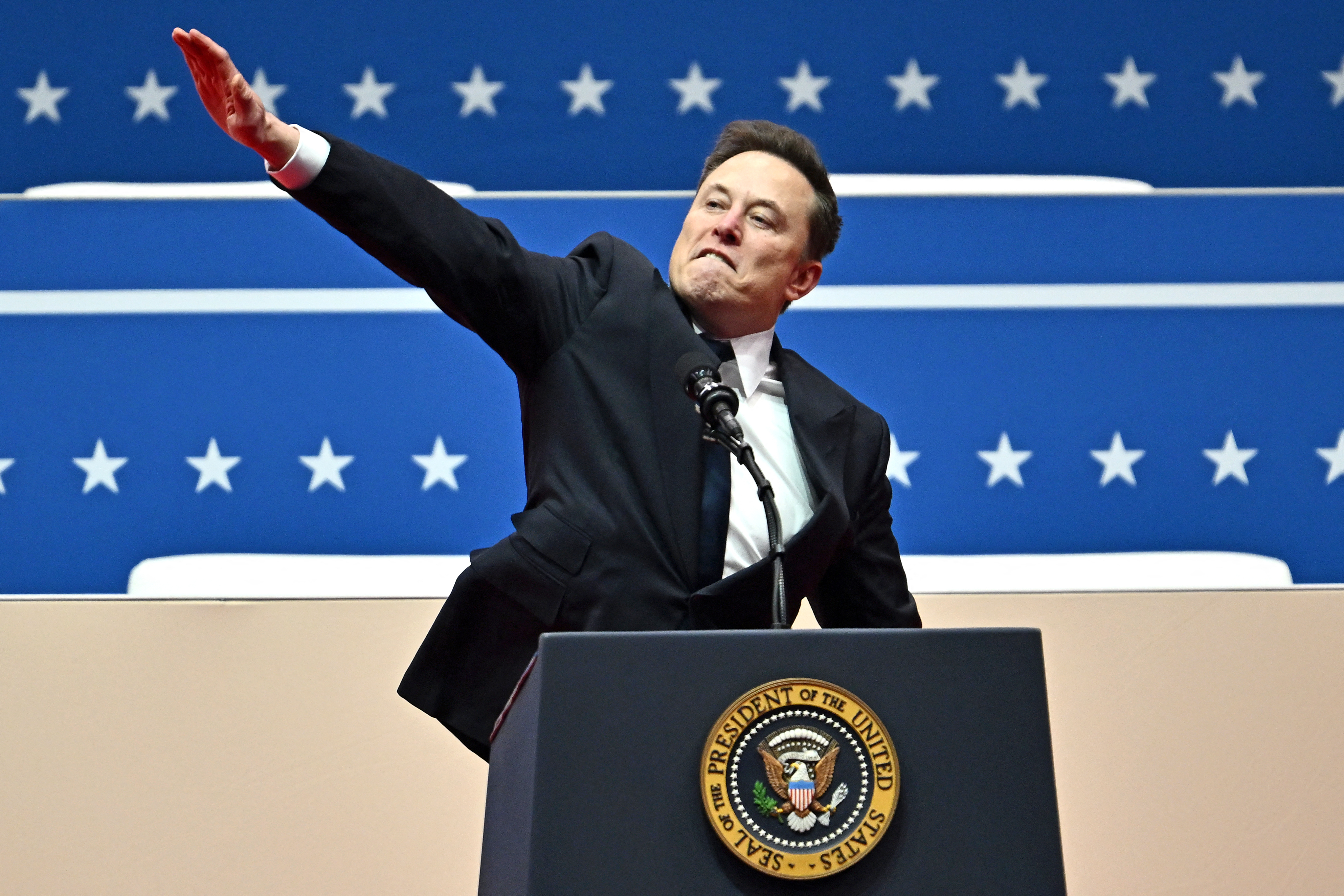 Elon Musk in a suit making a dynamic gesture at a podium with a symbol similar to a presidential seal, against a backdrop of stars