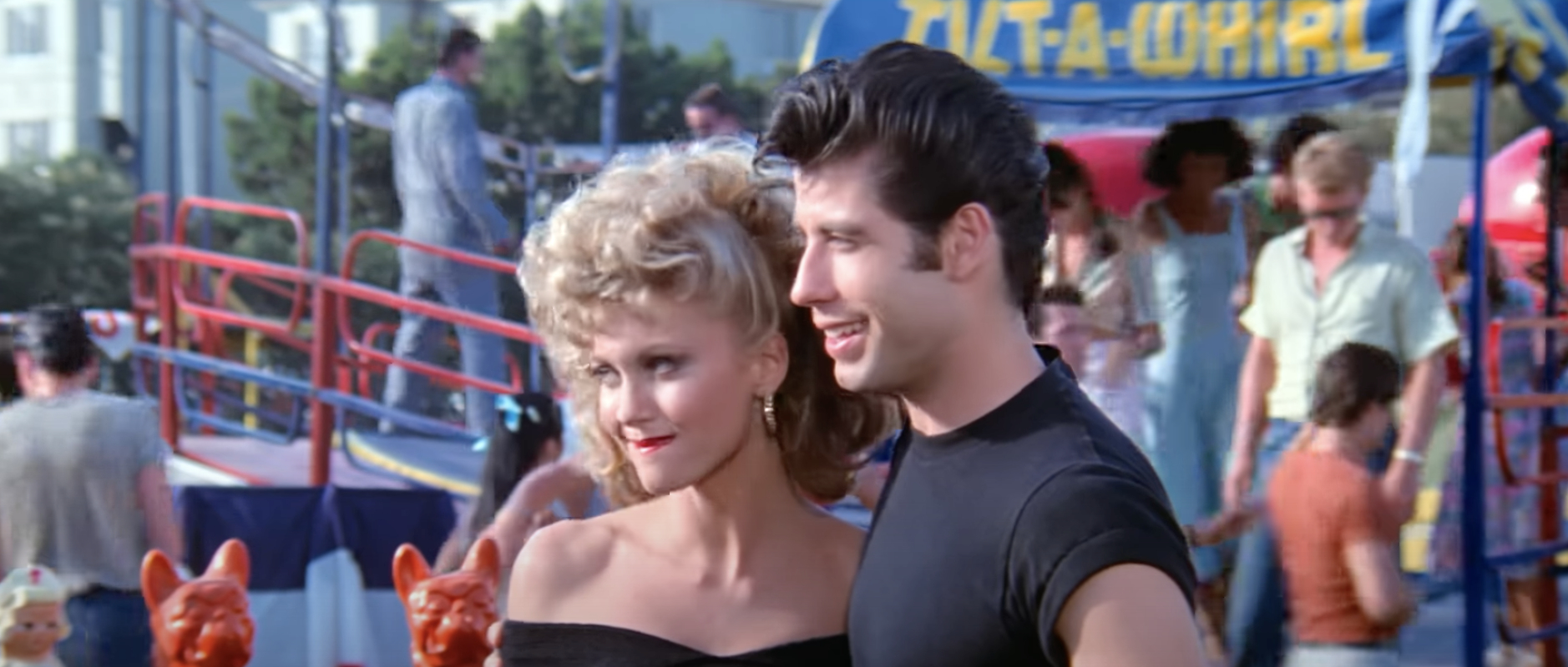 Olivia Newton-John and John Travolta stand beside each other in a still from "Grease