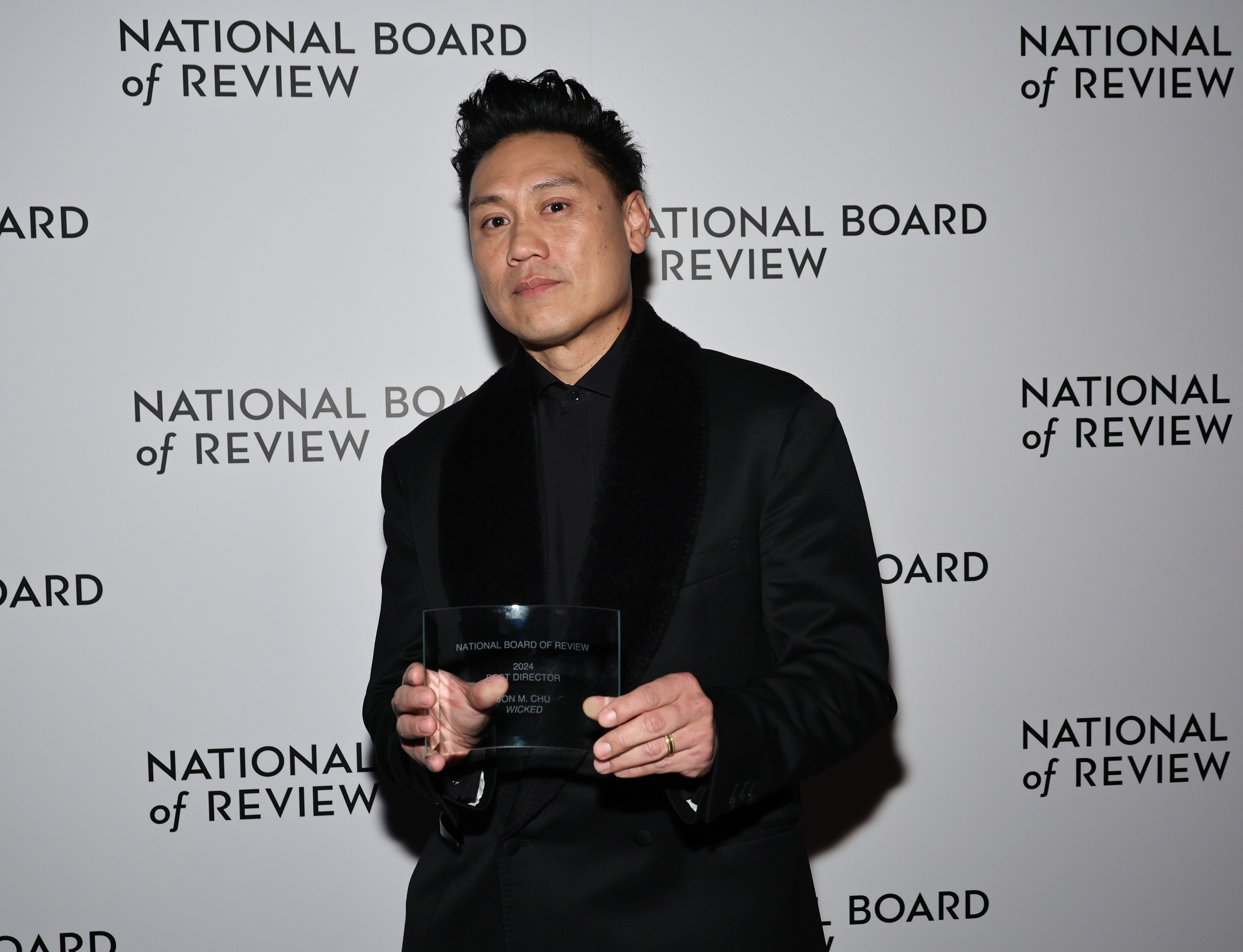Jon M. Chu in formal attire holding an award at the National Board of Review event