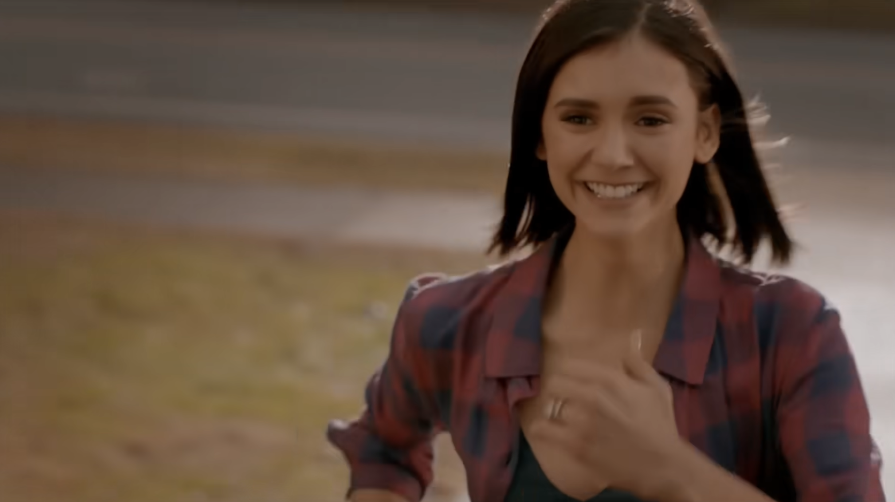 Person smiling broadly while running outdoors, wearing a checkered shirt