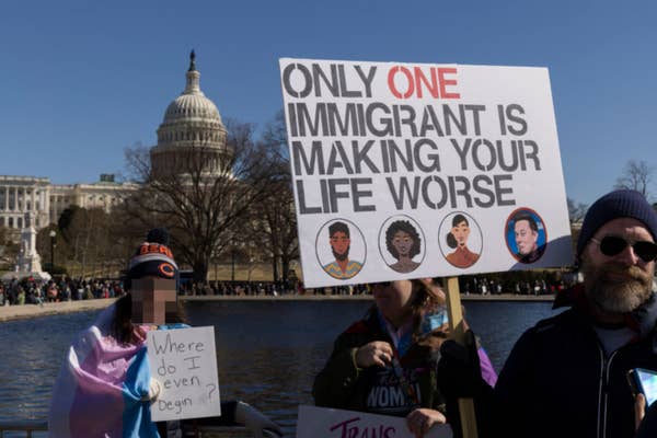 Protesters holding signs, including one stating: "Only one immigrant is making your life worse," in front of the U.S. Capitol building