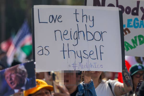 Protesters hold signs, including one reading "Love thy neighbor as thyself #AbolishIce," at a demonstration