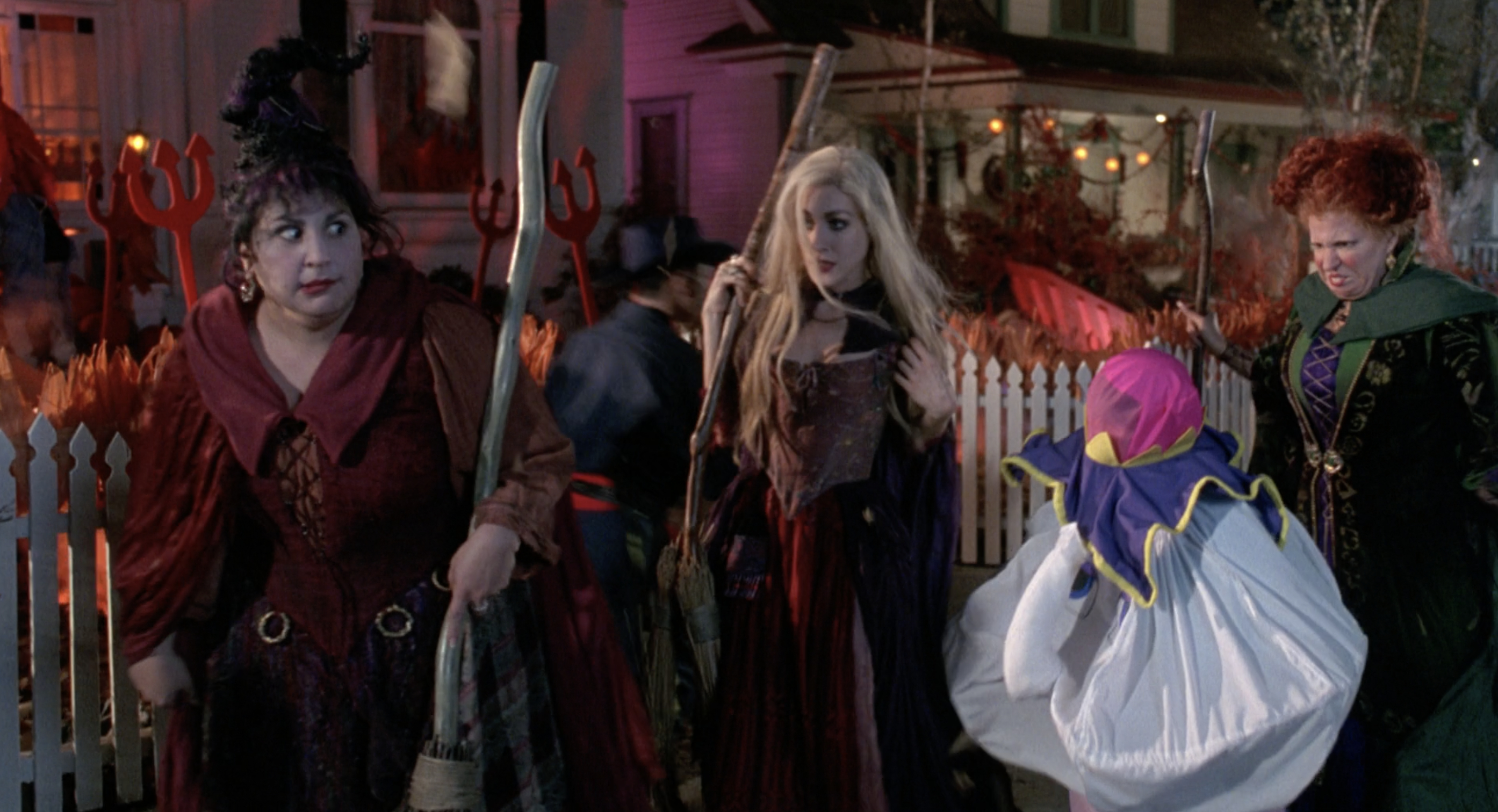 The Sanderson Sisters, holding broomsticks, walk past trick-or-treaters on Halloween Night in a scene from &quot;Hocus Pocus&quot;