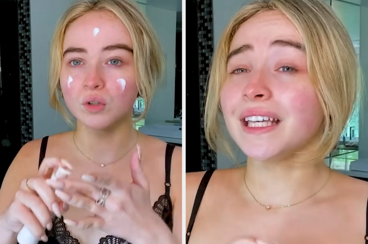 Sabrina Carpenter applies cream to her face in a bathroom, wearing a lacy top and necklace, demonstrating a skincare routine